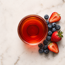 Load image into Gallery viewer, Glass of red tea with strawberries and blueberries on a marble surface
